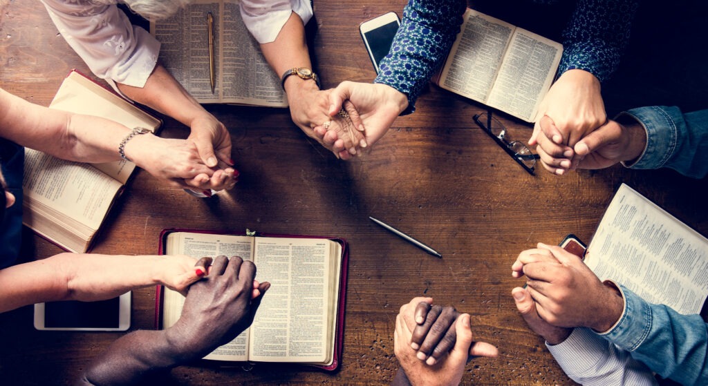 Group of people holding hands praying